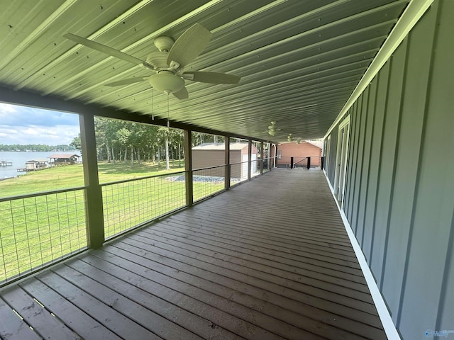 wooden deck featuring a ceiling fan, a water view, and a yard