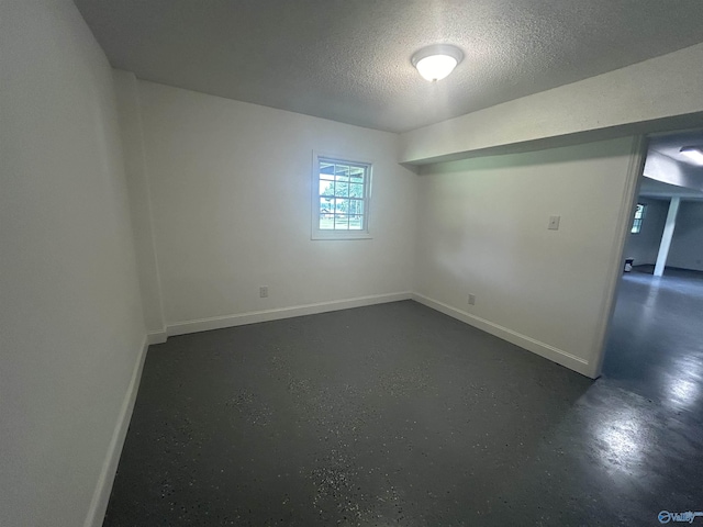 empty room with concrete floors, baseboards, and a textured ceiling