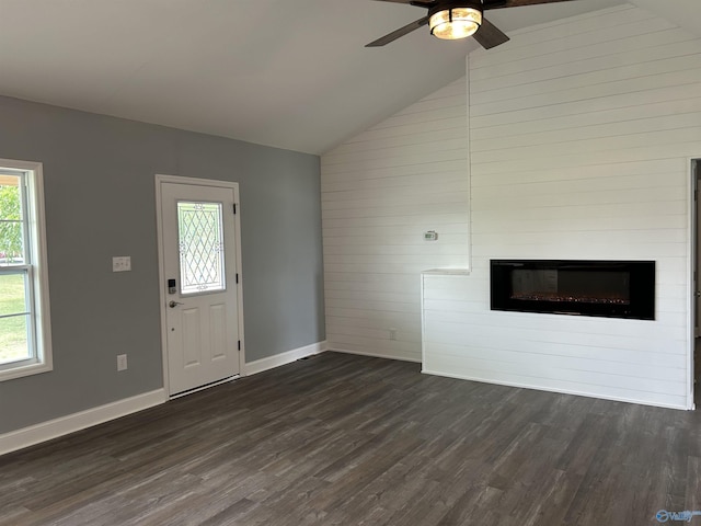 unfurnished living room featuring baseboards, dark wood finished floors, a ceiling fan, a glass covered fireplace, and vaulted ceiling