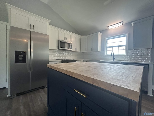 kitchen with a center island, stainless steel appliances, white cabinetry, a sink, and butcher block countertops