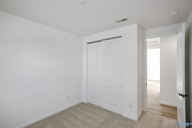 unfurnished bedroom featuring light colored carpet and a closet