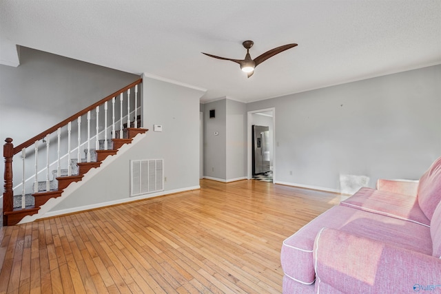 living room with hardwood / wood-style floors, ceiling fan, a textured ceiling, and ornamental molding