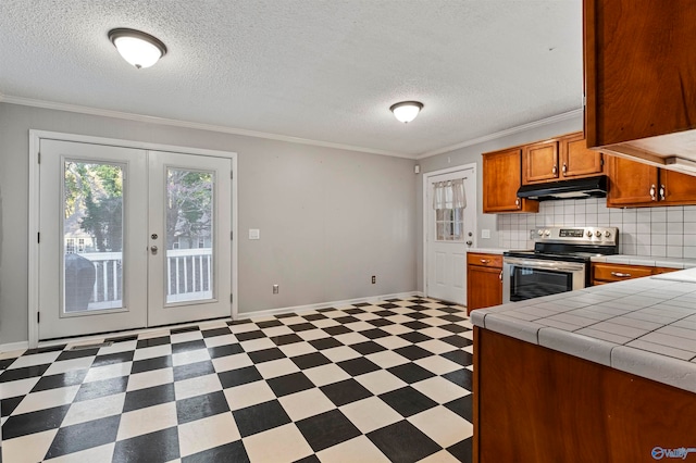 kitchen with tile countertops, tasteful backsplash, stainless steel range with electric cooktop, crown molding, and french doors