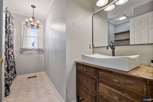 bathroom featuring vanity, a chandelier, a textured ceiling, and ornamental molding