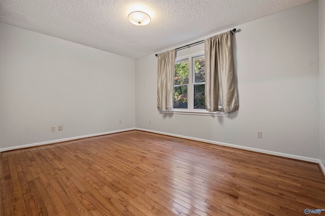 empty room featuring wood-type flooring and a textured ceiling