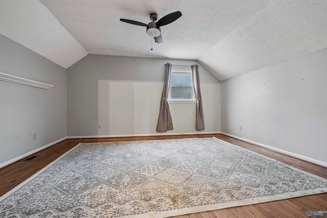 additional living space with vaulted ceiling, hardwood / wood-style flooring, ceiling fan, and a textured ceiling