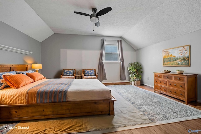 bedroom featuring hardwood / wood-style floors, ceiling fan, a textured ceiling, and lofted ceiling