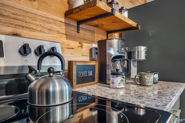 kitchen featuring light stone counters and wood walls