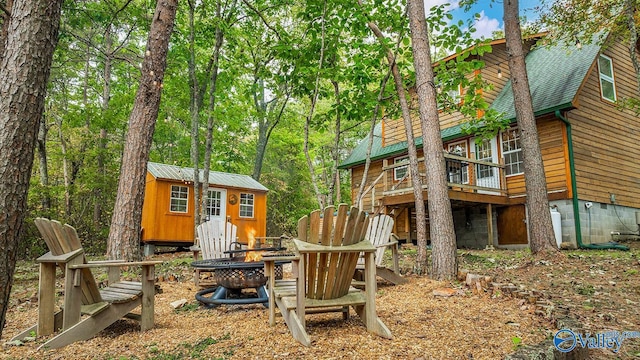 rear view of house featuring a deck, an outdoor fire pit, and an outbuilding