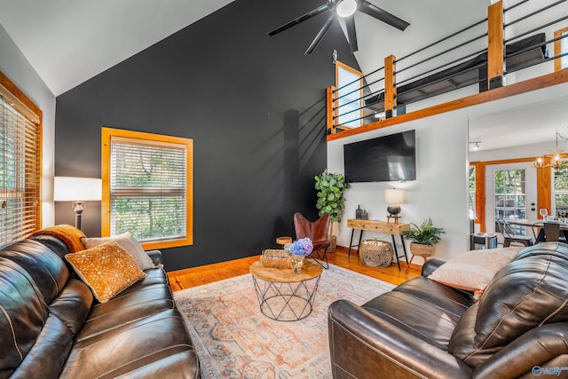 living room featuring ceiling fan with notable chandelier, wood-type flooring, high vaulted ceiling, and french doors