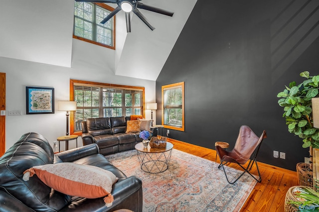 living room featuring light hardwood / wood-style flooring, a high ceiling, and ceiling fan