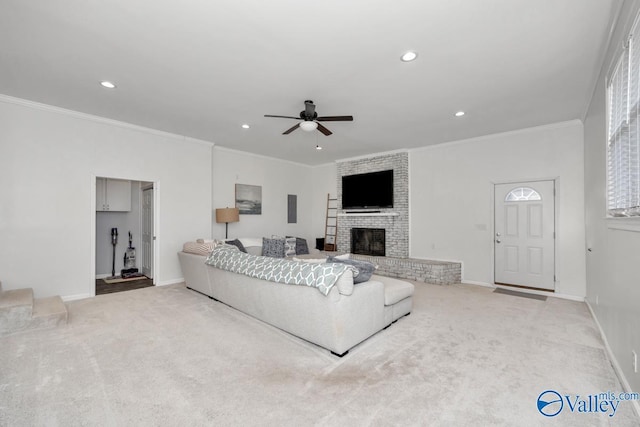 carpeted living room with ceiling fan, ornamental molding, and a brick fireplace