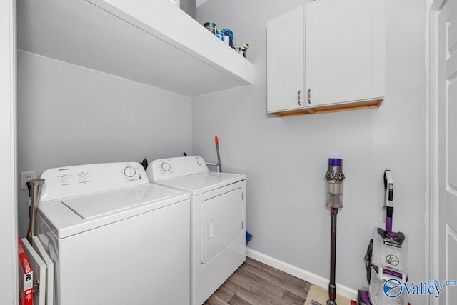 laundry room featuring cabinets, washing machine and dryer, and light wood-type flooring