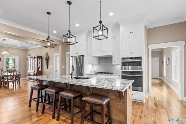 kitchen featuring white cabinets, pendant lighting, light hardwood / wood-style floors, and appliances with stainless steel finishes