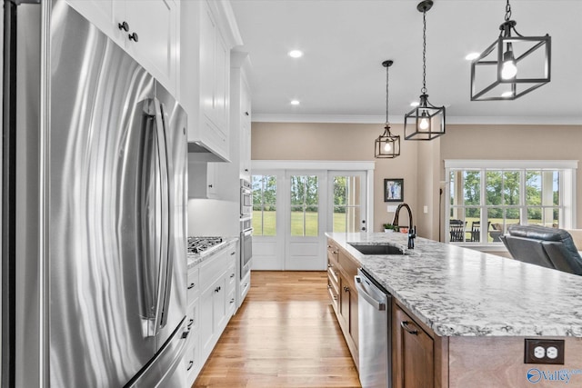 kitchen with appliances with stainless steel finishes, plenty of natural light, white cabinets, and sink