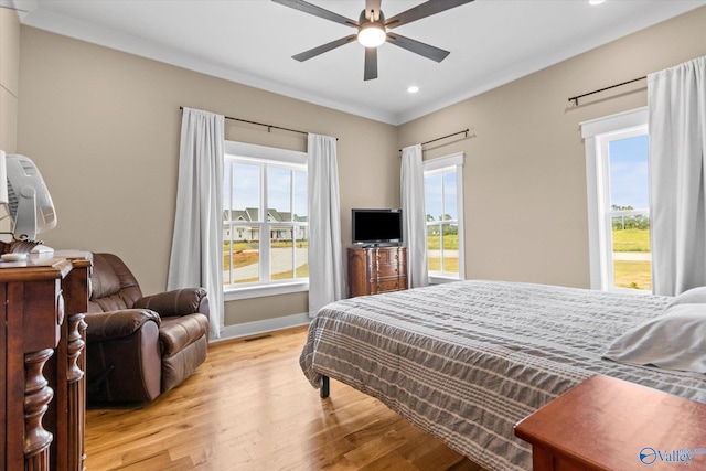 bedroom with ornamental molding, light hardwood / wood-style flooring, multiple windows, and ceiling fan