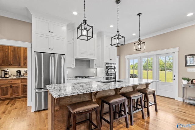 kitchen with light hardwood / wood-style floors, decorative light fixtures, white cabinetry, and stainless steel appliances