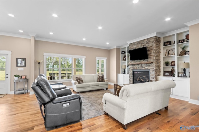 living room with a fireplace, light wood-type flooring, crown molding, and built in shelves