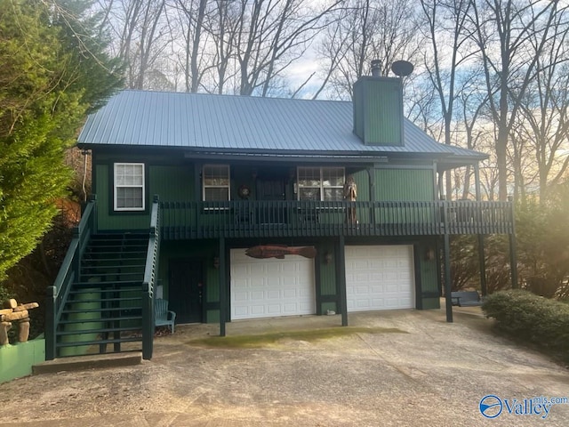 view of front of home with metal roof, a garage, driveway, stairway, and a chimney