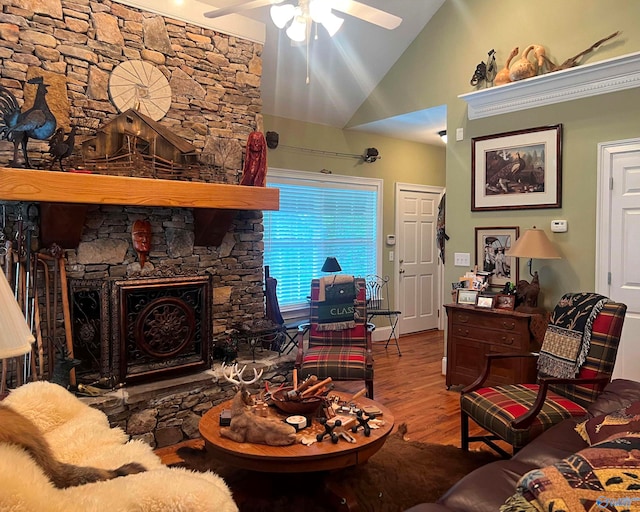 living room featuring a stone fireplace, wood-type flooring, vaulted ceiling, and ceiling fan