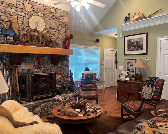 living area with high vaulted ceiling, a fireplace, wood finished floors, and a ceiling fan