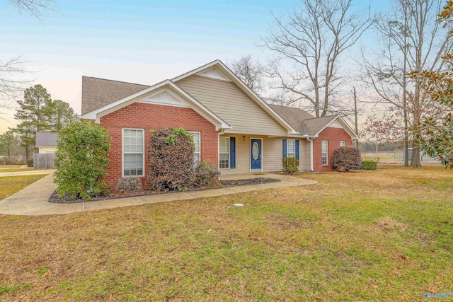 view of front of house featuring a front yard, brick siding, and fence