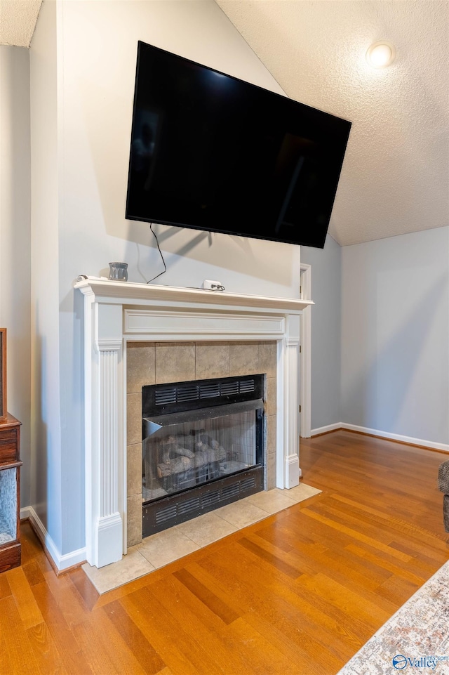 interior details with a textured ceiling, a fireplace, wood finished floors, and baseboards