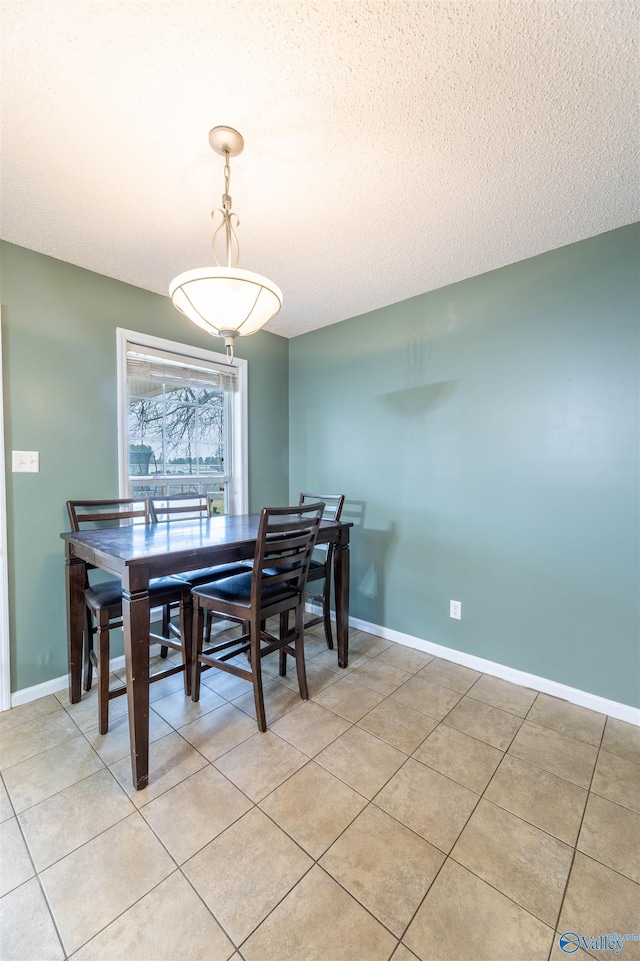 dining area featuring light tile patterned flooring, a textured ceiling, and baseboards