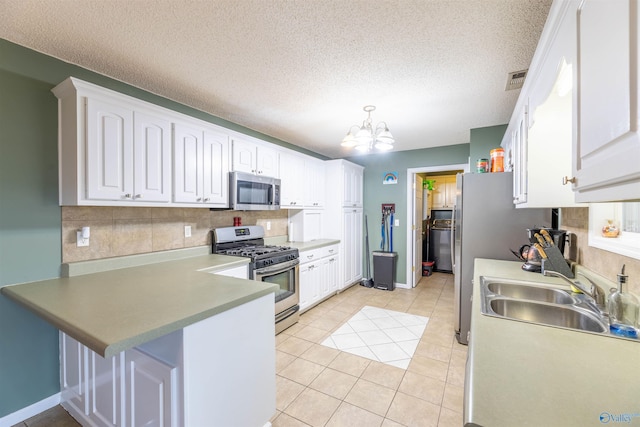 kitchen with a peninsula, appliances with stainless steel finishes, white cabinets, and a sink