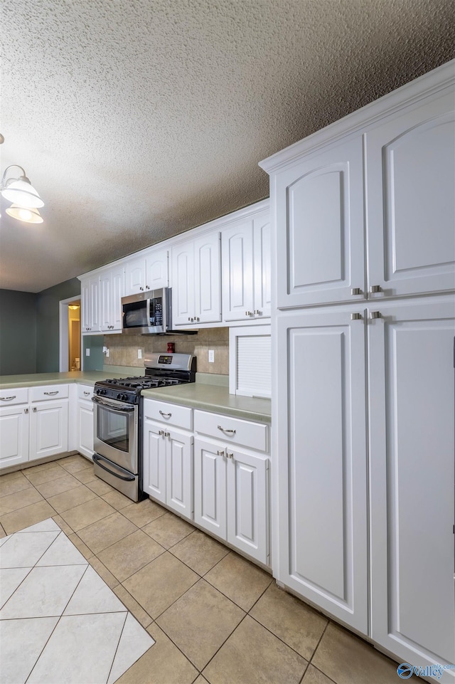 kitchen with stainless steel appliances, light tile patterned floors, light countertops, and white cabinetry