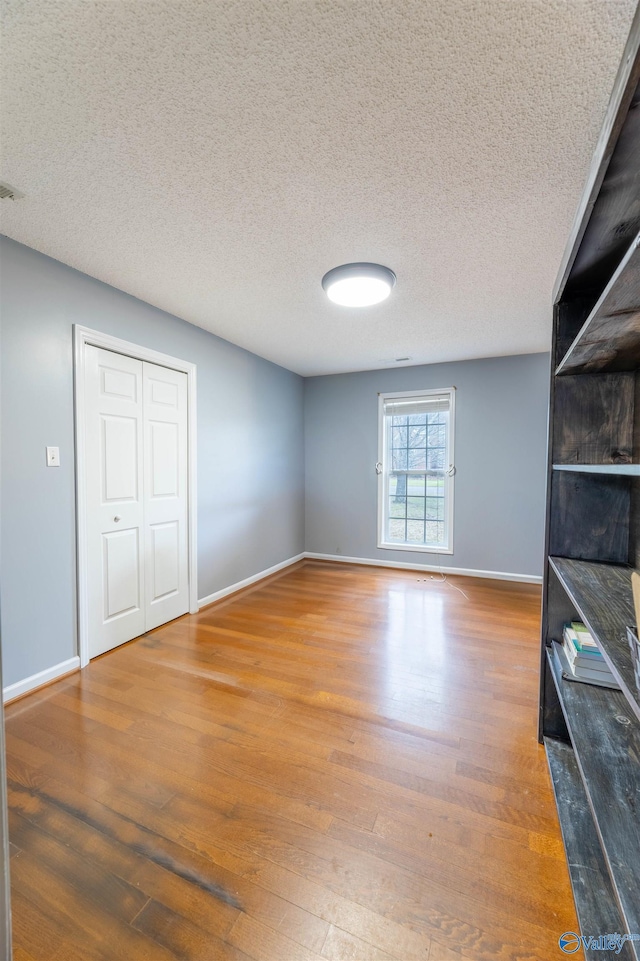 interior space featuring a textured ceiling, baseboards, and wood finished floors