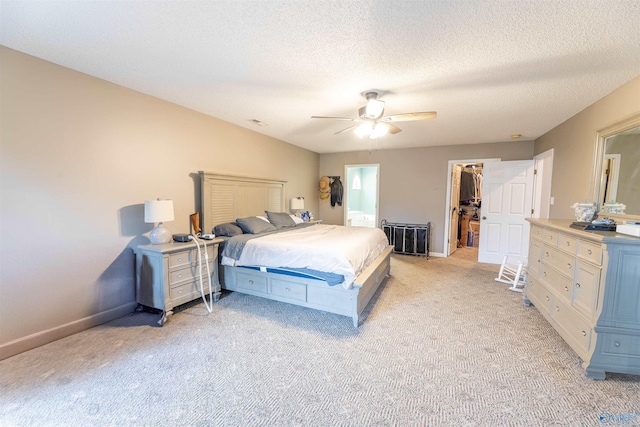 bedroom with a spacious closet, light carpet, ceiling fan, a textured ceiling, and baseboards