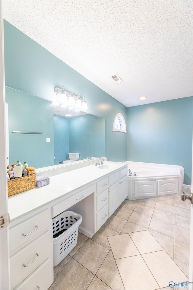 full bath featuring a textured ceiling, a garden tub, visible vents, vanity, and tile patterned floors