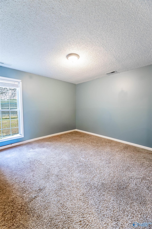 carpeted spare room featuring baseboards, visible vents, and a textured ceiling