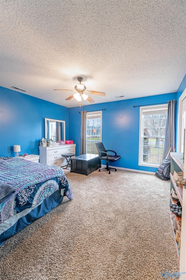 carpeted bedroom with ceiling fan, a textured ceiling, and visible vents