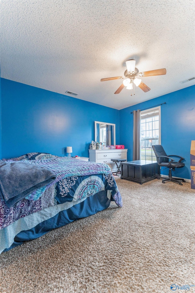 bedroom featuring ceiling fan, carpet floors, a textured ceiling, and visible vents