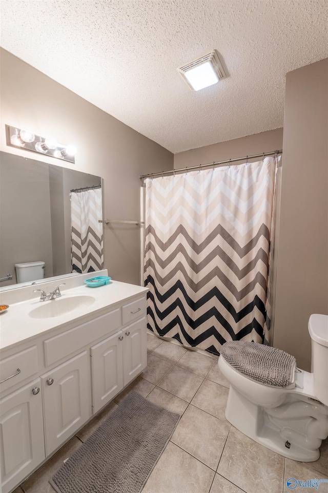 bathroom with visible vents, toilet, a textured ceiling, vanity, and tile patterned floors