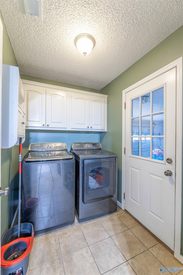 laundry area featuring cabinet space, light tile patterned floors, visible vents, and separate washer and dryer