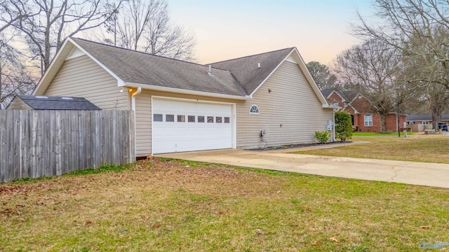 view of property exterior with an attached garage, fence, driveway, a lawn, and roof with shingles