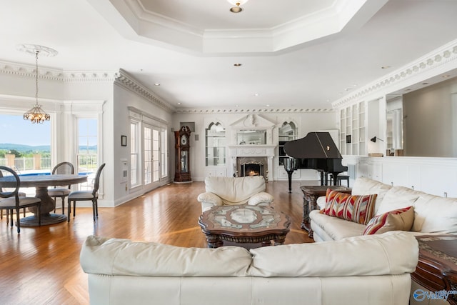 living room featuring an inviting chandelier, hardwood / wood-style flooring, a raised ceiling, and ornamental molding