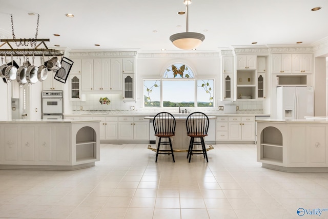 kitchen featuring light tile patterned floors, a center island, tasteful backsplash, and white appliances