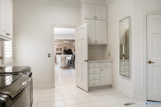 kitchen with washing machine and dryer, white cabinets, and light tile patterned floors