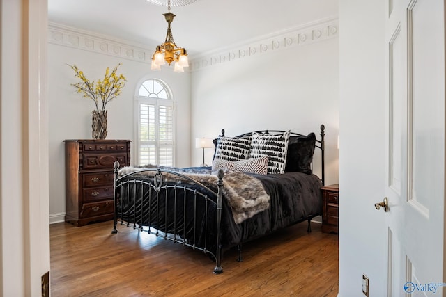 bedroom featuring a notable chandelier, hardwood / wood-style flooring, and crown molding