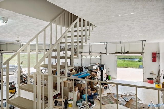 stairs featuring a textured ceiling, ceiling fan, and concrete floors