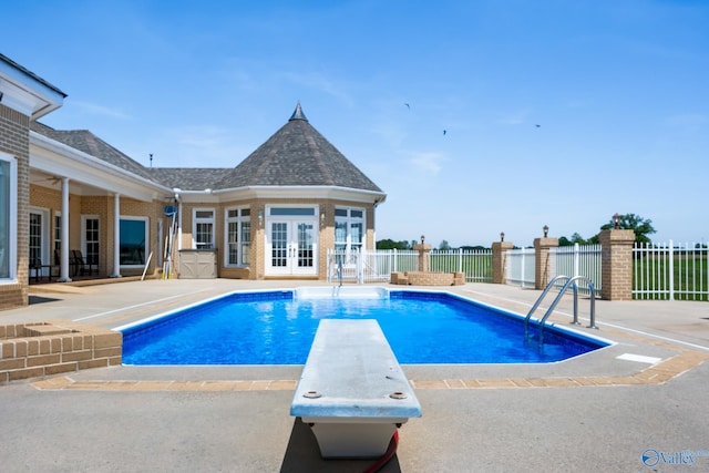 view of pool featuring a diving board, a patio area, and french doors