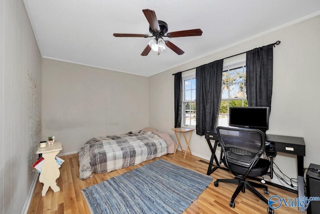 bedroom featuring ornamental molding, wood finished floors, a ceiling fan, and baseboards