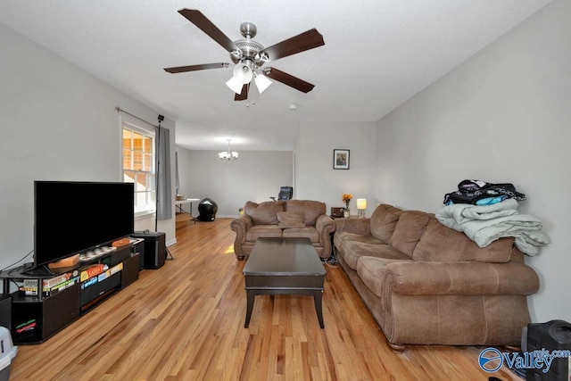 living area with light wood-style flooring and ceiling fan with notable chandelier