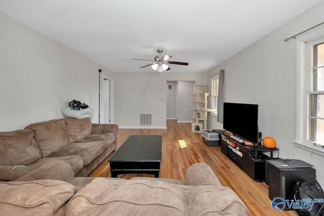 living room with a ceiling fan, visible vents, and wood finished floors