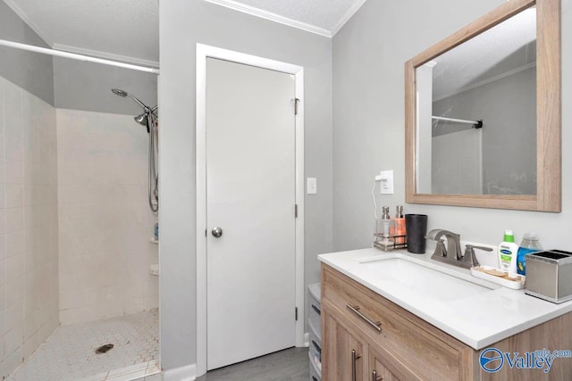 full bathroom with a textured ceiling, tiled shower, and vanity