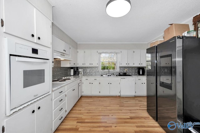 kitchen with light wood-style floors, white cabinets, a sink, white appliances, and under cabinet range hood